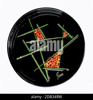 Arte floreale fluttuante con frutti di bosco d'arancia e corsetto in un vaso nero rotondo isolato su sfondo bianco Foto Stock