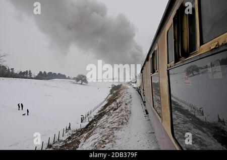 Gli escursionisti si fermano sul treno a vapore passando in un paesaggio innevato, la Severn Valley Railway, Worcestershire Foto Stock