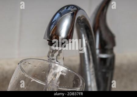 Vetro al rubinetto di acqua e di acqua di riempimento con contaminazione di piombo Foto Stock