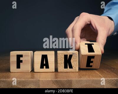 Tedesco falso o concetto di fatto con uomo d'affari mano che gira blocchi di legno Foto Stock