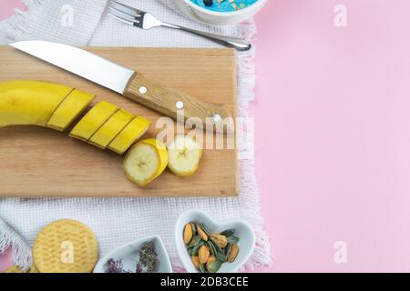 La banana tagliata su un vassoio di legno, accanto alla ciotola dell'insalata sono i sandnut di mandorle e i semi di zucca. Foto Stock