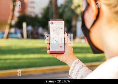 Stock foto di una giovane donna utilizzando un Coronavirus tracking app sul suo telefono mentre è in strada Foto Stock