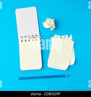 apri il notebook in linea e una matita di legno blu, accanto alle pagine strappate e stropicciate, vista dall'alto Foto Stock