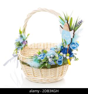 Piccolo cesto di Pasqua per bambini decorato con delicati fiori blu pastello e con pollo decorativo in legno su sfondo bianco Foto Stock