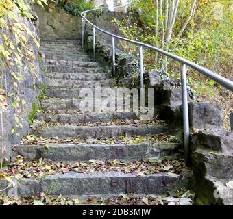 Scala esterna in pietre naturali con una leggera curva piena di foglie d'autunno 2 Foto Stock