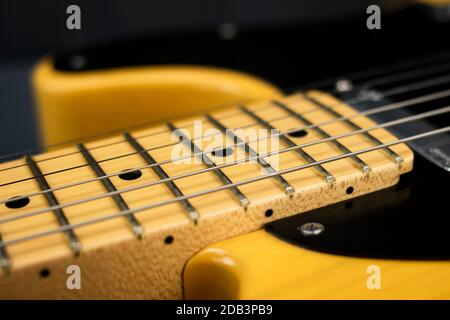 Dettagli di archi in acciaio, collo e tasti di una classica chitarra elettrica rock e blues, luminosa, in legno grigio Foto Stock