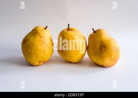 Vita still con tre pere gialle su sfondo bianco. Foto Stock