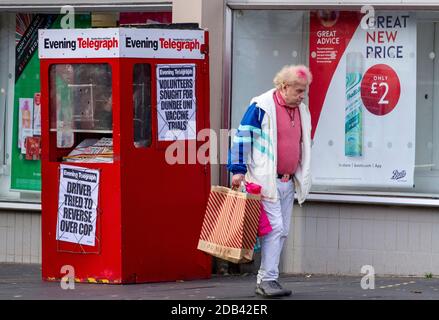 Dundee, Tayside, Scozia, Regno Unito. 16 Nov 2020. Notizie del Regno Unito Covid-19 Lockdown. Le persone che camminano per le strade di Dundee con pochi negozi di abbigliamento essenziali aperti dal livello 3 più rigoroso Covid-19 Lockdown restrizione è stato imposto. Un uomo alla moda con i capelli di colore rosa è consapevole delle linee guida di distanziamento sociale e l'uso di maschere facciali a piedi, mentre trasportano una grande borsa di carta Primark durante il suo shopping di Natale in centro città, in un freddo e soleggiato pomeriggio di novembre. Credit: Dundee Photographics/Alamy Live News Foto Stock