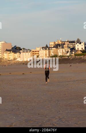 Saint Malo, Francia - 16 Settembre 2018: la donna è in esecuzione lungo la spiaggia di Saint Malo, Brittany, Francia Foto Stock