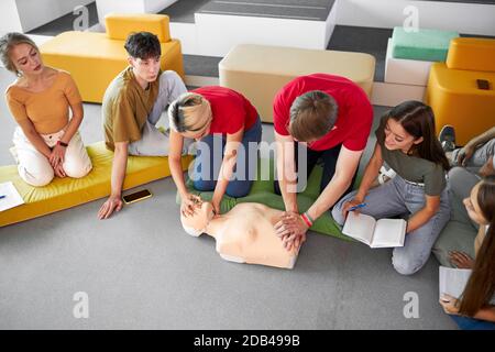 Gruppo di giovani diversi pratica di addestramento di primo soccorso a mano, corso di primo soccorso in CPR manichino. Concetto di abilità di formazione per salvare vite umane, medicina Foto Stock