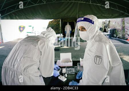 Operatore medico in DPI che esegue un tampone nasale e della gola su una persona nel veicolo attraverso la finestra dell'auto, centro di test mobile COVID-19. Torino, Italia - 2 novembre Foto Stock