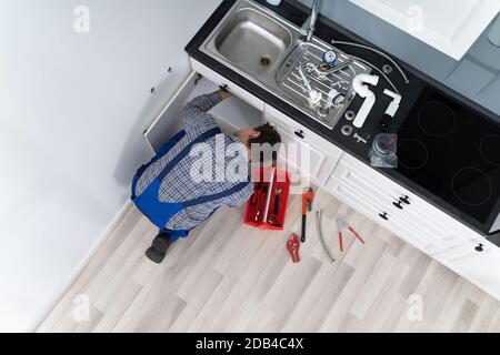 Lavoratore Sdraiato A Pavimento Riparazione Cucina Lavello Con Chiave Regolabile Foto Stock