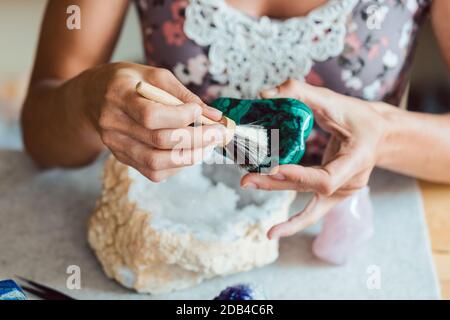 Giovane donna che spolverò una malachite con un pennello Foto Stock