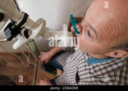 Uomo anziano che testa la funzione di respirazione mediante spirometria Foto Stock