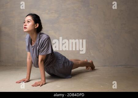 Ritratto di splendida giovane donna asiatica che pratica yoga indoor. Bella ragazza pratica cobra asana in classe. Foto Stock
