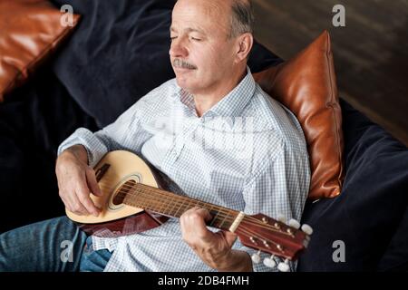 Senior uomo a casa di imparare a suonare la chitarra Foto Stock