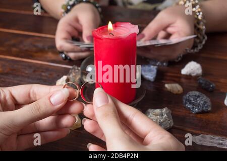 Una donna zingara guess un fiammifero di amore usando gli anelli di nozze e le schede di fortuna-dire da candlelight.Fortune che dice con gli anelli di nozze, la fortuna che dice fo Foto Stock