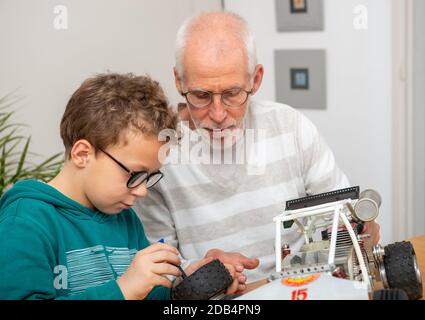 nonno e figlio ragazzino che riparano una macchina radio-controllata modello a casa Foto Stock