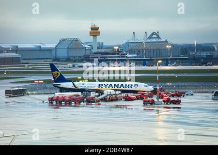 Ryanair Aircraft per la manutenzione della linea di taxi nell'aeroporto di Amburgo, tra i veicoli di servizio. Vista dalla finestra terminale in un giorno nuvoloso dopo la pioggia Foto Stock