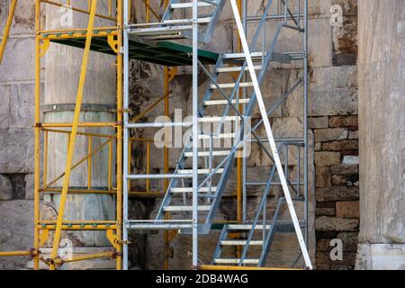 Impalcatura in metallo con scale installate all'esterno dell'edificio vecchio durante i lavori di ristrutturazione sulla strada, vista della chioccia Foto Stock