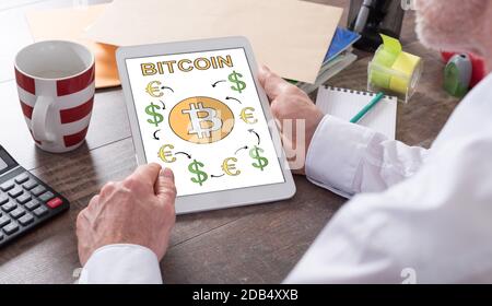 Il concetto di Bitcoin mostrato su un tablet tenuto da un uomo Foto Stock