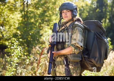 coraggiosa donna caucasica è impegnata in armi da caccia pistola o fucile, indossando tuta militare. bersaglio sparato. cacciatrice femminile in foresta selvaggia, natura. caccia di successo. caccia sport concetto Foto Stock