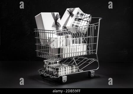 Carrello pieno di scatole regalo su sfondo nero. Sopping sul Black Friday Concept Foto Stock