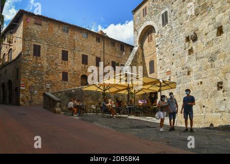 Scorrete il borgo medievale di San Gimignano, patrimonio dell'umanità dell'UNESCO, con persone e turisti in caffè all'aperto, Siena, Toscana, Italia Foto Stock