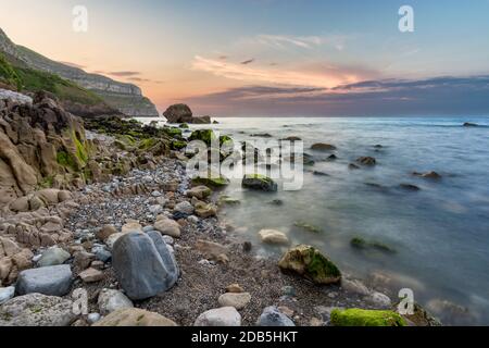 Arancione vibrante tramonto estivo sulla costa rocciosa di Llandudno nel Galles del Nord, Regno Unito. Foto Stock