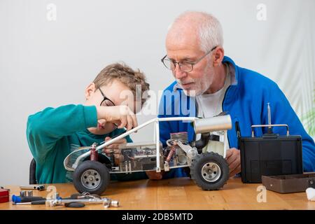 nonno e figlio ragazzino che riparano una macchina radio-controllata modello a casa Foto Stock