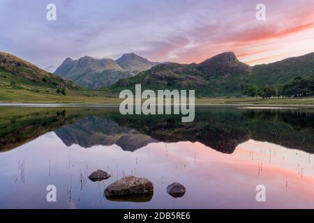 Riflessi chiari di montagne in acqua a Blea Tarn nel Distretto dei Laghi Inglese all'alba. Foto Stock