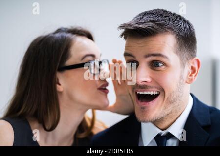 Ritratto di donna felice Whispering segreto o interessante Gossip all uomo bello nel suo orecchio Foto Stock