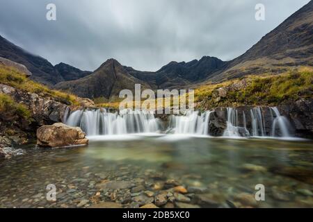 Moody nuvole sulla catena Cuillin con cascata alle piscine Fairy, Isola di Skye, Scozia, Regno Unito. Foto Stock