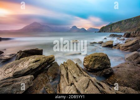 Moody cielo drammatico sulla gamma Cuillin con interessanti rocce a forma in primo piano. Preso a Elgol, Scozia, Regno Unito. Foto Stock