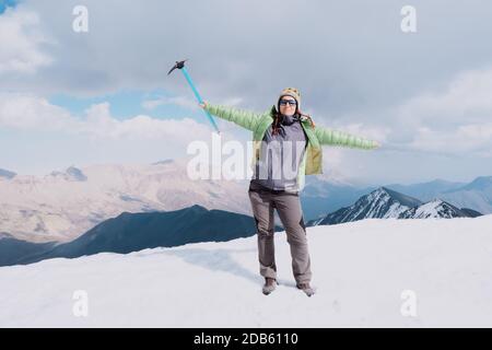 Donna felice escursionista con un rompighiaccio sulla cima di una montagna. Tempo neve. Foto Stock