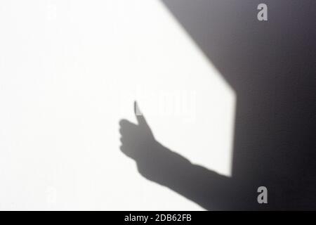 silhouette shadow mano facendo tumbi su parete bianca, isolato in casa spazio per il testo Foto Stock