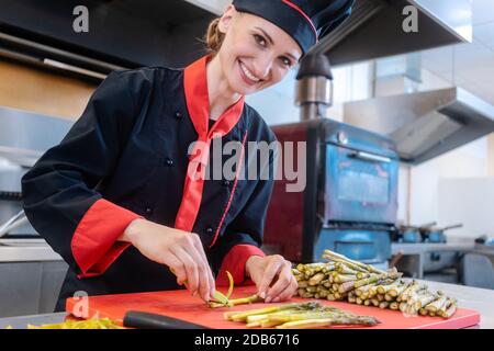 Una chef femminile che taglia strisce di asparagi Foto Stock