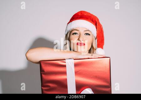 Bella donna che fa le labbra del gallo e posa con regalo di Natale Foto Stock
