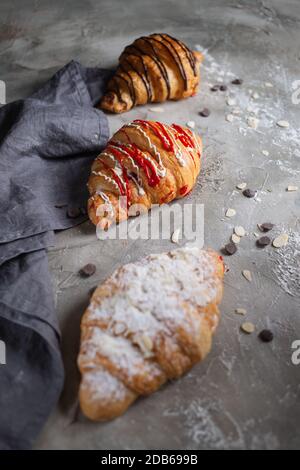 tre croissant freschi su tavola di legno e tovagliolo di stoffa Foto Stock