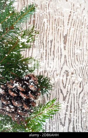 Vista dall'alto decorazione natalizia fatta di rami di abete con cono di pino e fiocchi di neve volanti su sfondo woden con spazio di copia. Modello di carta di Natale e Capodanno. Foto Stock