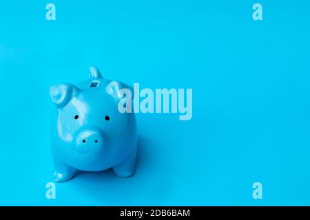Blu piggy banca sorriso isolato su sfondo blu. Concetto di finanza, risparmio di denaro. Foto Stock