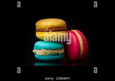Torte colorate di macaron. Piccole torte francesi. Macaroni francesi dolci e colorati isolati su sfondo nero Foto Stock