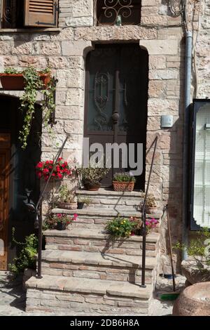 Fiori in vaso sui gradini di pietra casa medioevale in Toscana Foto Stock