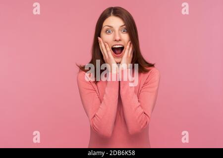 Donna sorpresa estremamente scioccata con i capelli marroni urlando tenendo le mani sulle guance, cant credere nella sua vittoria, stupore. Studio interno girato iso Foto Stock