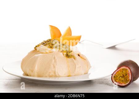 Dessert Pavlova su piatto bianco. Pavlova torta guarnita con panna montata e frutto della passione. Foto Stock