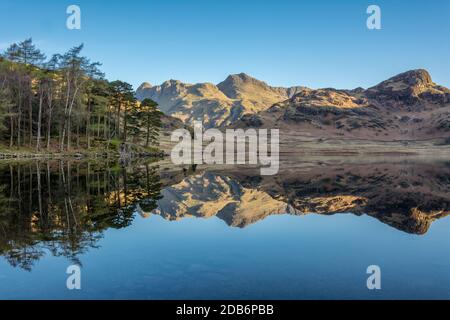 Riflessi chiari perfetti nel lago dei Langdale Pikes a Blea Tarn, nel Distretto dei Laghi Inglese, con cielo blu chiaro in una mattinata soleggiata. Foto Stock