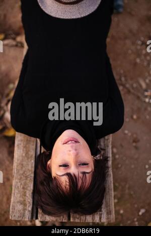 Donna che pratica lo yoga e si stende sdraiato su una panchina Foto Stock