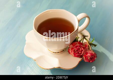 Tè pomeridiano in classico bianco con rose su sfondo di legno blu Foto Stock