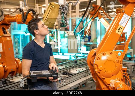 programmazione di bracci robot per un nuovo prodotto da parte di un tecnico di produzione. Foto Stock