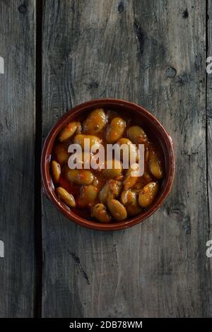 Fagioli greci gigantes in piastra di argilla su tavola di legno Foto Stock